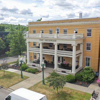 Elevated drone shot of The Sherwood Hotel showing covered porch, lush landscaping, and THE SHERWOOD text on portico