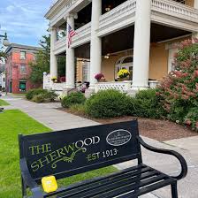 Branded bench with THE SHERWOOD EST 1913 and building behind