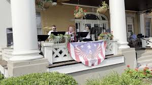 Live band performing on front porch for July 4th with patriotic bunting