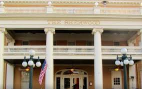 Detail of upper facade showing THE SHERWOOD lettering, balustrade, and pediment