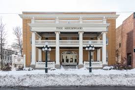 The Sherwood Hotel in winter with fresh snow, bright facade against white landscape, and holiday decorations