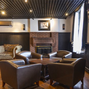 Lounge with leather chairs, brick fireplace, and tin ceiling