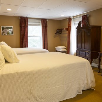 Two double bed room with white linens, burgundy curtains, dark wood armoire, and reading art on wall