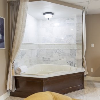 Oversized whirlpool jacuzzi tub with marble tile surround and elegant curtain draping in the bridal suite