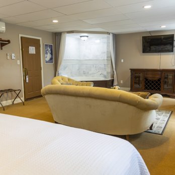 King suite with bed, tufted sofa, and jacuzzi visible behind curtain