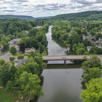 Aerial of the Chenango River with bridge, lush green trees, and hills in the distance
